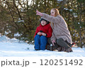 Mother and son sitting on a bench in the winter forest and talking 120251492