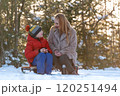 Portrait of young woman and child boy during picnic in winter in forest. Mother and son drink hot tea from thermos. 120251494