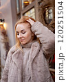 Portrait of beautiful woman in a fur coat outdoor. Attractive middle-aged woman. City street. Holiday mood. Vertical frame 120251504