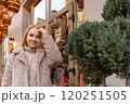 Blond young woman with beautiful eyes in a fur coat on a festive street. Christmas mood. Holiday weekend 120251505
