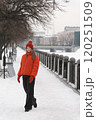A young woman in a red jacket walks along the embankment in winter. 120251509