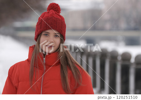 Portrait of a young girl in a red jacket on a background of winter landscape 120251510
