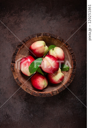 ripe nectarine, in a wooden plate, brown background, top view, no people, 120251861