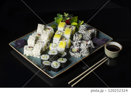 Seth sushi on a black background.Menu of the Japanese restaurant. Several sushi lined on a plate with bamboo sticks and soy sauce Seth sushi on a black background.Menu of the Japanese restaurant. Several sushi lined on a plate with bamboo sticks and soy sauce 120252324