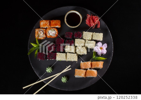 Seth sushi on a black background.Menu of the Japanese restaurant. Several sushi lined on a plate with bamboo sticks and soy sauce Seth sushi on a black background.Menu of the Japanese restaurant. Several sushi lined on a plate with bamboo sticks and soy sauce 120252338