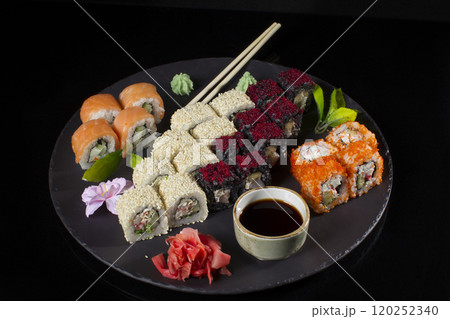 Seth sushi on a black background.Menu of the Japanese restaurant. Several sushi lined on a plate with bamboo sticks and soy sauce 120252340