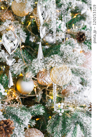 Christmas tree with frosted snowy branches decorated with silver and gold ornaments with lights 120253319