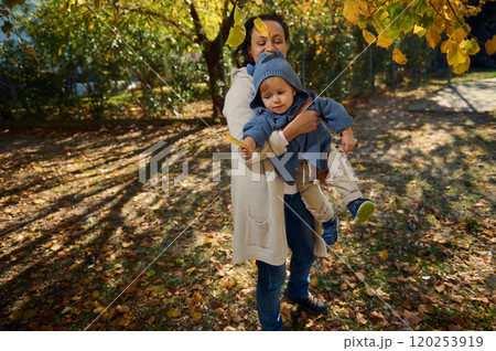 Mother holding child in a sunny autumn park landscape 120253919