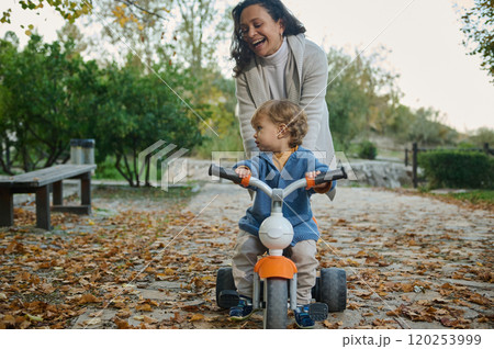 Joyful autumn day with mother and toddler on tricycle outside Joyful autumn day with mother and toddler on tricycle outside 120253999