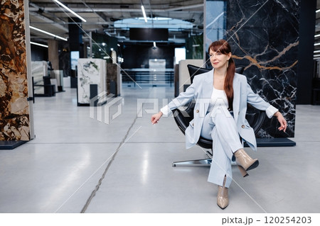 Woman in light blue suit posing in a modern office space Woman in light blue suit posing in a modern office space 120254203