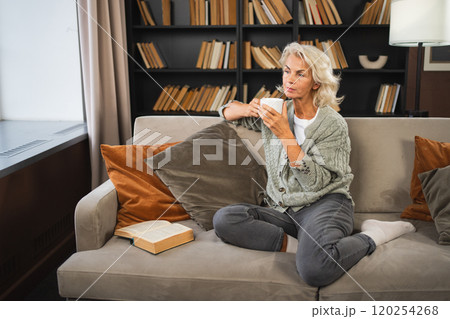 Good morning autumn winter fall vibe. Comfort relaxed senior old elderly woman drinking hot beverage tea coffee in sofa at home. Mature woman resting enjoy calm morning at home alone. Pension concept Good morning autumn winter fall vibe. Comfort relaxed senior old elderly woman drinking hot beverage tea coffee in sofa at home. Mature woman resting enjoy calm morning at home alone. Pension concept 120254268