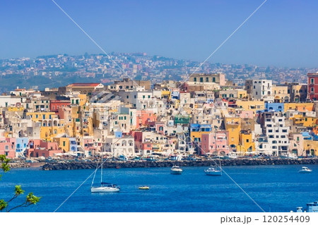 Procida in sunny summer day. Colorful houses, cafes and restaurants, fishing boats and yachts in Marina Corricella, blue sky and azure sea, Procida Island, Italy. 120254409