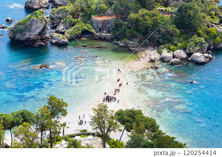 Tourists walk along narrow path surrounded by azure waters that connects Isola Bella to mainland Taormina, Sicily, Italy Tourists walk along narrow path surrounded by azure waters that connects Isola Bella to mainland Taormina, Sicily, Italy 120254414
