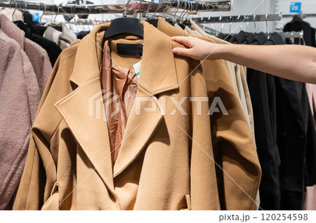 Customer Hand Picking Coat from Clothing Rack in Store 120254598
