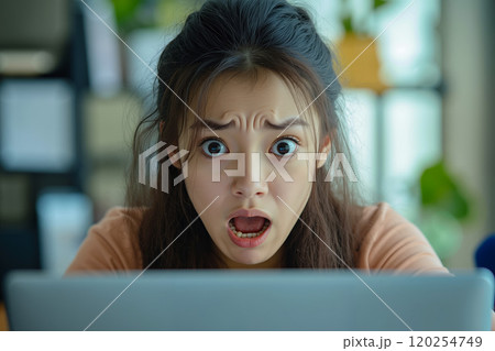 A woman with a surprised look on her face looking at a laptop A woman with a surprised look on her face looking at a laptop 120254749
