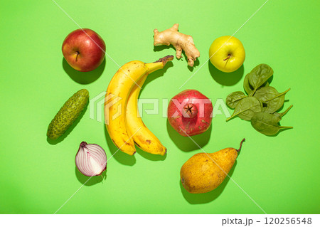 Fresh fruits, vegetables and spices creating a colorful arrangement on green background top view, high contrast with hard light 120256548
