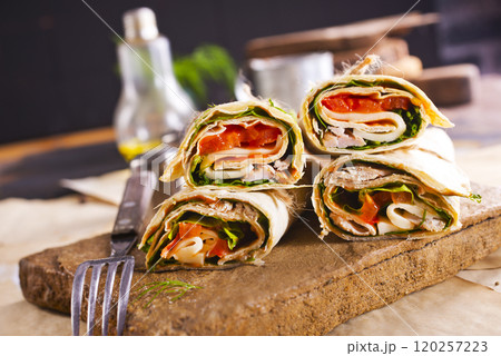Sliced sandwich tortilla with tomatoes , salad , cream cheese and ham . 120257223