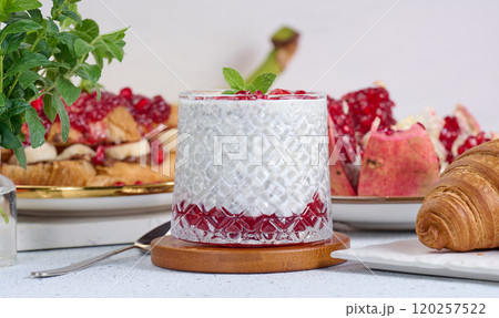 Glass of yogurt with chia seeds, pomegranate seeds and baked croissants on table 120257522
