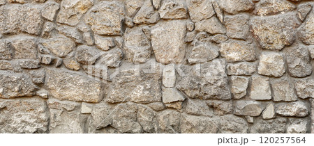 Old coarse pattern panoramic stone wall made of various square natural stones and blocks in beige, ocher and brown 120257564