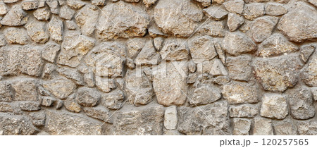 Old coarse pattern panoramic stone wall made of various square natural stones and blocks in beige, ocher and brown Old coarse pattern panoramic stone wall made of various square natural stones and blocks in beige, ocher and brown 120257565