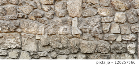 Old coarse pattern panoramic stone wall made of various square natural stones and blocks in beige, ocher and brown Old coarse pattern panoramic stone wall made of various square natural stones and blocks in beige, ocher and brown 120257566
