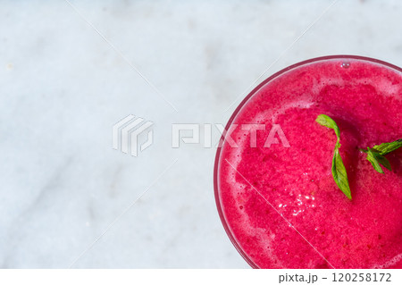 Top-down view of red frozen drink with mint on marble. Concept of refreshing summer beverage and tropical vibes Top-down view of red frozen drink with mint on marble. Concept of refreshing summer beverage and tropical vibes 120258172