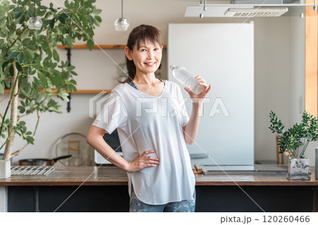 自宅トレーニング後にペットボトルのミネラルウォーターで水分補給をするアジア人女性 自宅トレーニング後にペットボトルのミネラルウォーターで水分補給をするアジア人女性 120260466