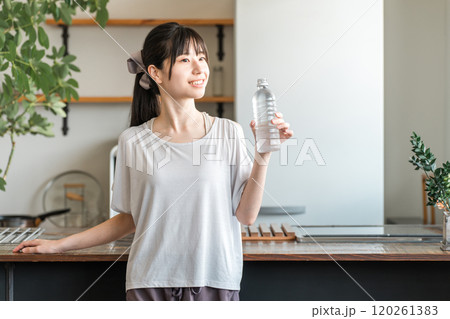自宅トレーニング後にペットボトルのミネラルウォーターで水分補給をするアジア人女性 自宅トレーニング後にペットボトルのミネラルウォーターで水分補給をするアジア人女性 120261383