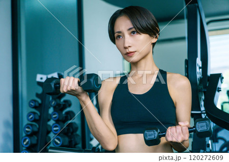 ジムでダンベルで腕を鍛える女性 120272609