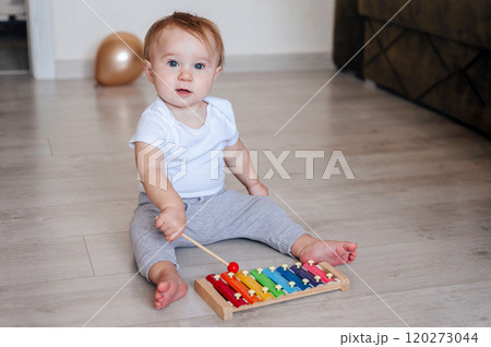 little girl in white bodysuit sitting on floor and playing with colorful toy little girl in white bodysuit sitting on floor and playing with colorful toy 120273044
