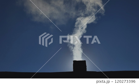 Chimney smoke against a clear blue sky, representing coziness, home, and winter warmth 120273396
