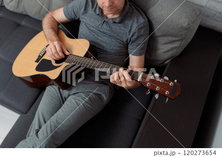 man guitarist playing guitar at home. Relaxing and sitting on sofa man guitarist playing guitar at home. Relaxing and sitting on sofa 120273654