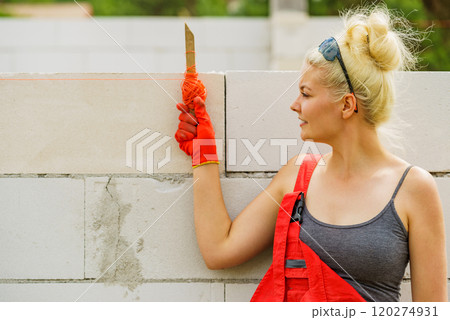 Woman using string as level in wall construction. Woman using string as level in wall construction. 120274931