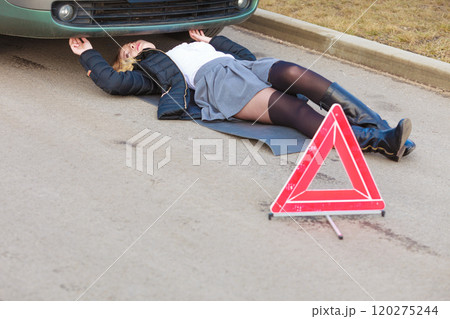 Woman, repairing broken car lying under it Woman, repairing broken car lying under it 120275244
