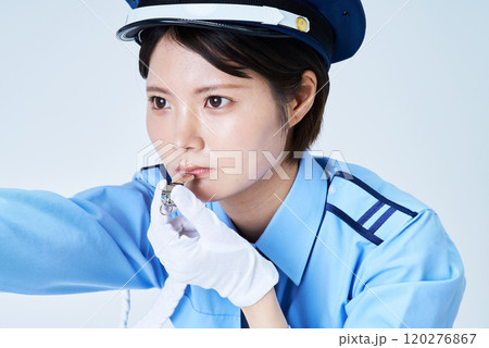 笛を鳴らしながら指さしをする女性警備員 120276867