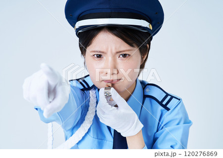 笛を鳴らしながら指さしをする女性警備員 120276869