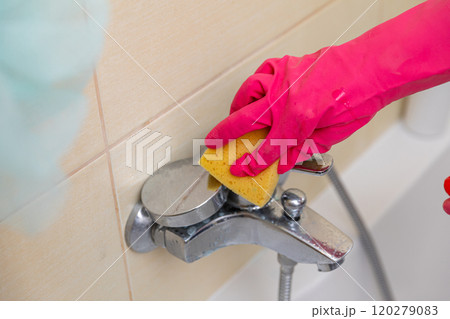 Cleaning your bathroom faucet with a sponge and gloves ensures hygiene and appearance 120279083