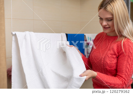 A woman is efficiently handling fluffy towels in a beautifully modern bathroom space A woman is efficiently handling fluffy towels in a beautifully modern bathroom space 120279162