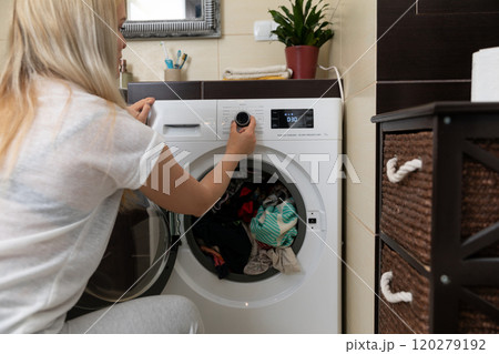 A woman is effectively operating a washing machine in a modern, stylish laundry room setting 120279192