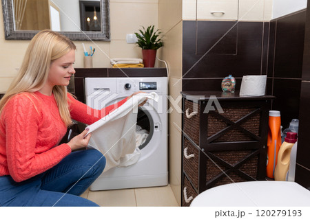 A woman is engaged in the task of doing laundry in a modern, stylish bathroom featuring a washer 120279193