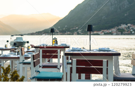 A charming waterfront dining setup with mountain views, perfect for a serene and romantic evening meal by the lake. 120279923