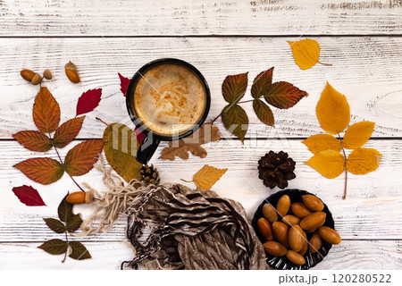 Autumn, fall leaves, hot steaming cup of coffee and a warm scarf on wooden table background. Seasonal, morning coffee, Sunday relaxing and still life concept. Autumn, fall leaves, hot steaming cup of coffee and a warm scarf on wooden table background. Seasonal, morning coffee, Sunday relaxing and still life concept. 120280522