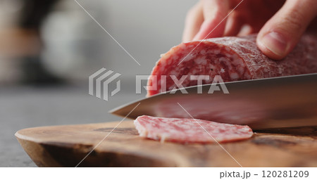 man slicing salame sausage on olive wood board man slicing salame sausage on olive wood board 120281209