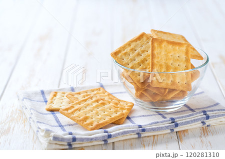 Traditional dry biscuits square shape in a clear glass bowl with on a light kitchen table, selective focus. 120281310