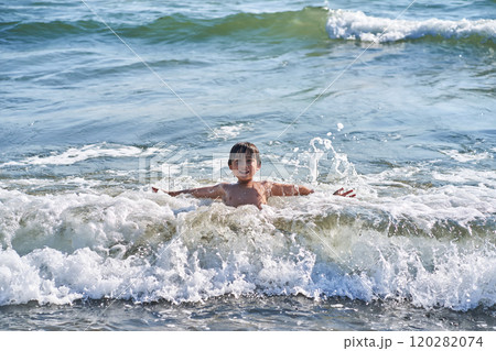 An 11 year old boy in having fun in the sea waves. 120282074