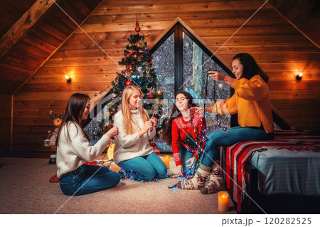 Christmas and new year. A group of young happy women socialize and untangle the lights. Scandinavian style interior 120282525