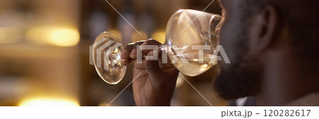 Website banner with unrecognizable African American highly skilled sommelier drinking white wine to check its taste 120282617