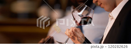 Website banner with unrecognizable woman holding polished crystal glass with red wine and smelling scent 120282626