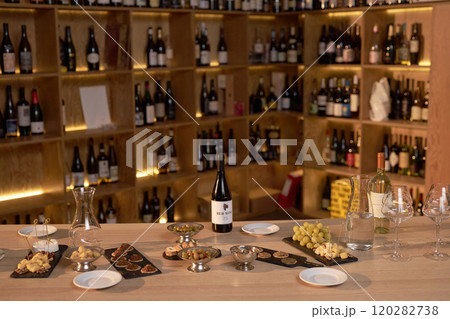 High angle shot of tasting table with bottles of red and white wine, crystal glasses and snack prepared for degustation in wine cellar 120282738