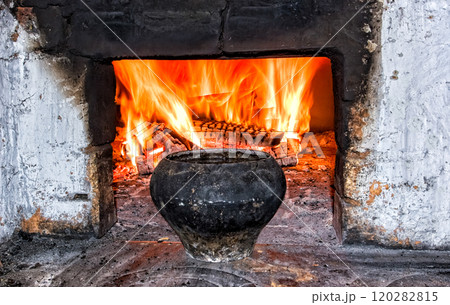 Brick oven with cast iron pot and burning firewood at the village house 120282815